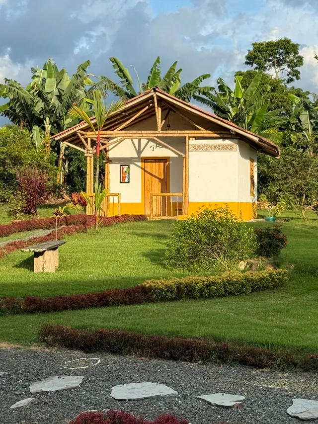 Cabaña familiar con techo de madera rodeada de jardín y plataneras