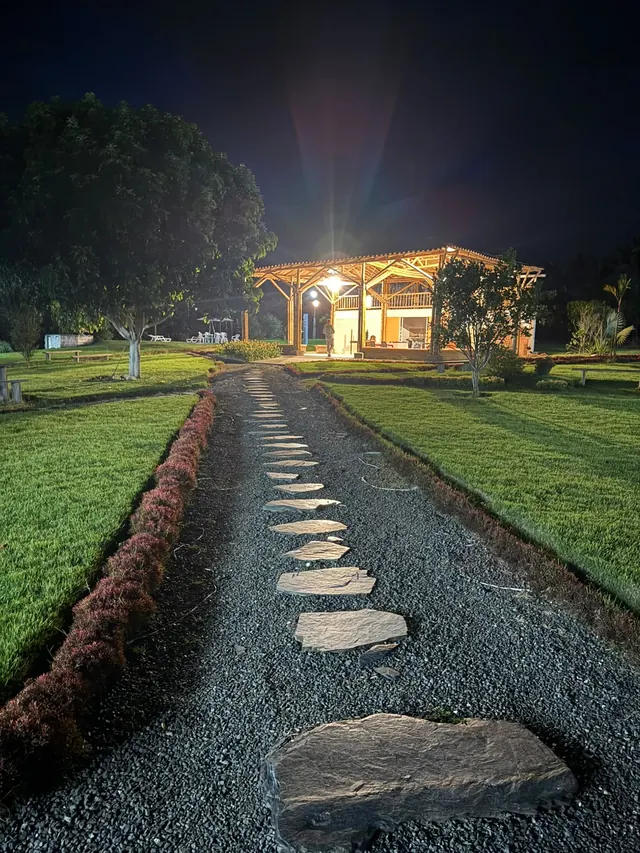 Sendero de piedra iluminado hacia el salón de noche