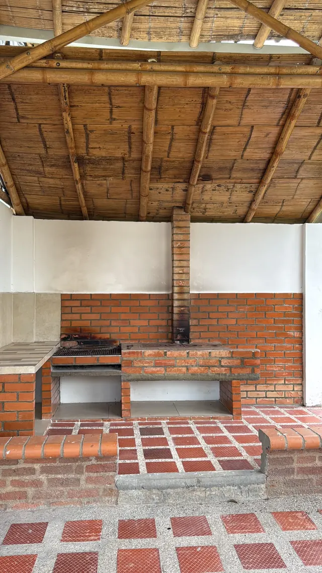 Zona de parrilla en ladrillo bajo techo de madera