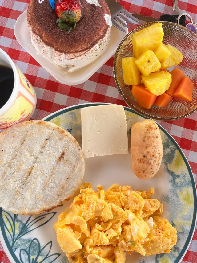 Desayuno típico con arepa, huevos, queso, pan y fruta fresca