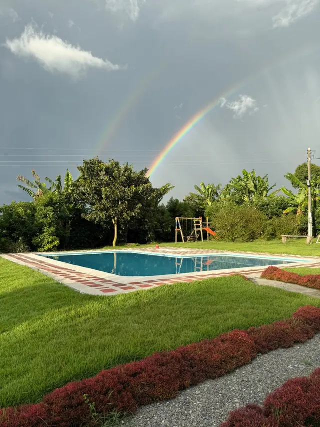 Piscina y jardines con un doble arcoíris