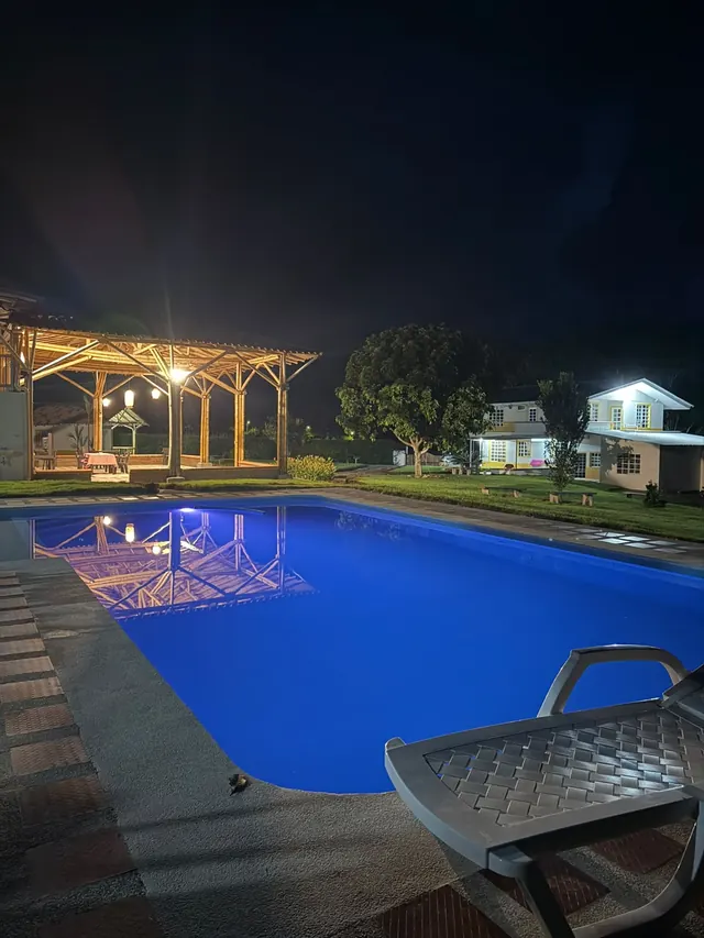 Piscina iluminada de noche junto al salón